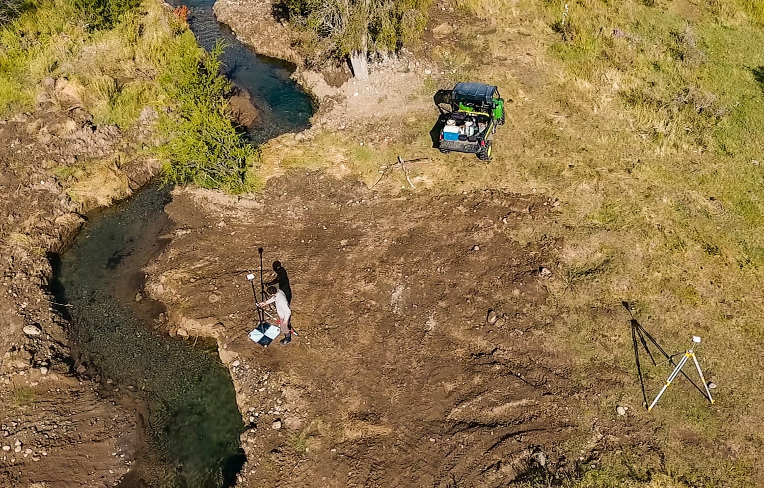 Vista aérea de un cauce recién abierto con un técnico midiendo con GPS